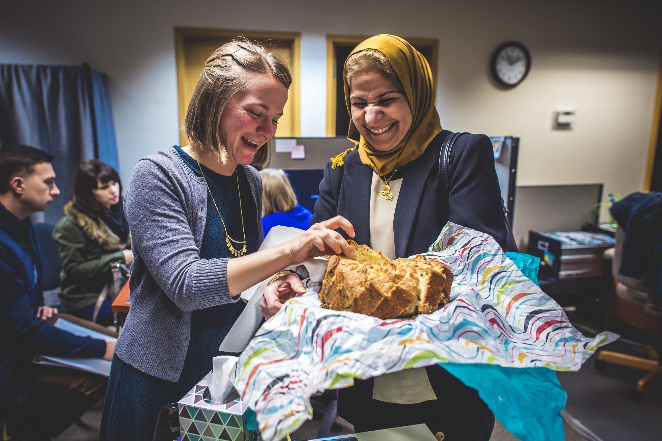 Two women smiling and laughing with baked bread