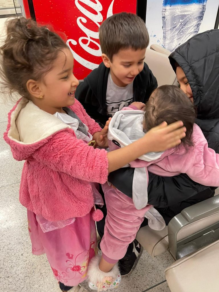 A refugee child is hugged by her siblings when she arrives at the Memphis airport.