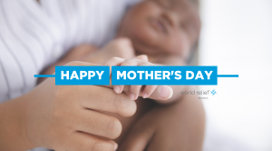 A woman holds a baby's hand.