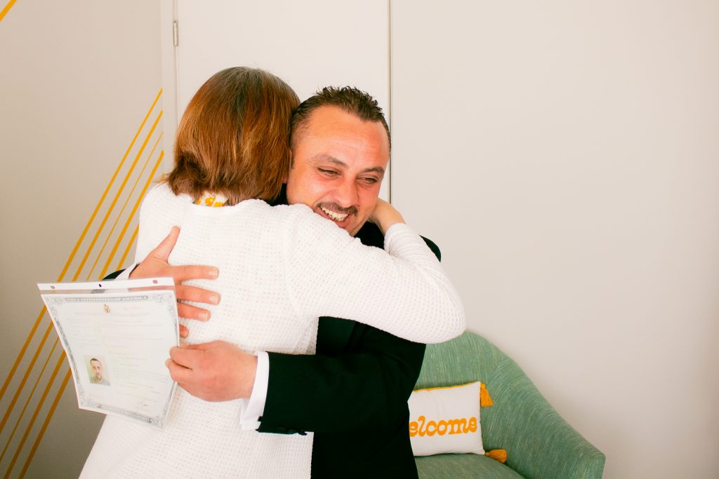 Image of a World Relief staff member hugging a client after he obtained his US citizenship.