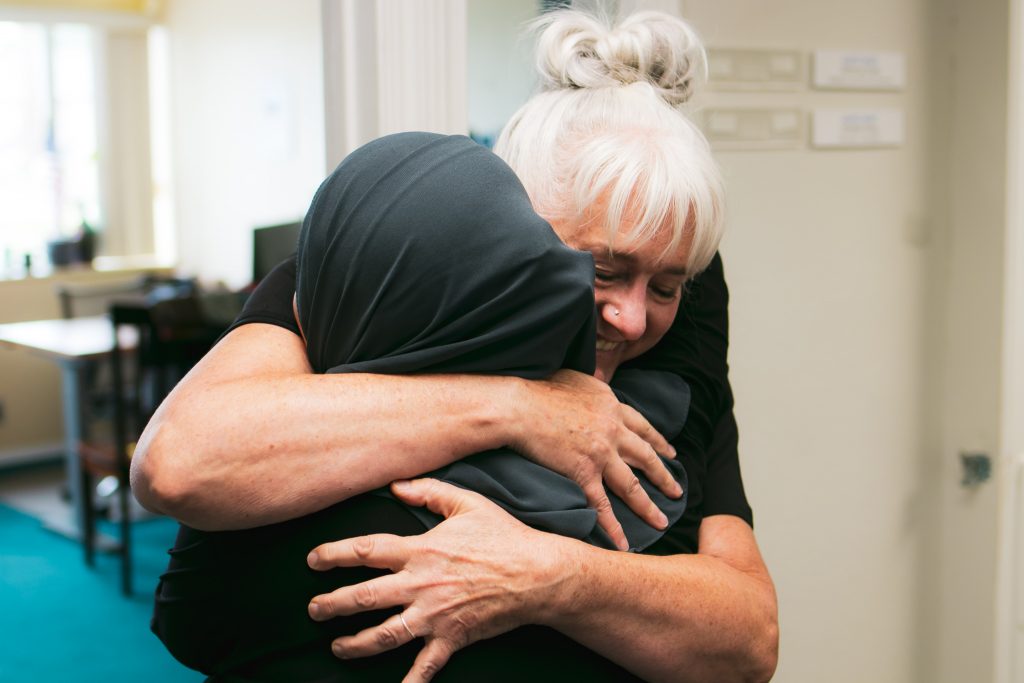 Image of the author hugging a fellow staff member after meeting for the first time.