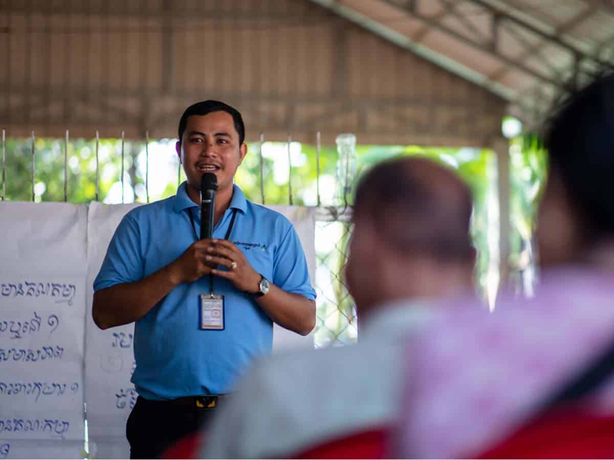 Man speaking to crowd of people in open-air structure