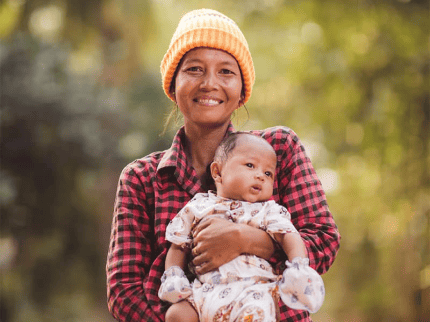Women in hat smiling holding baby