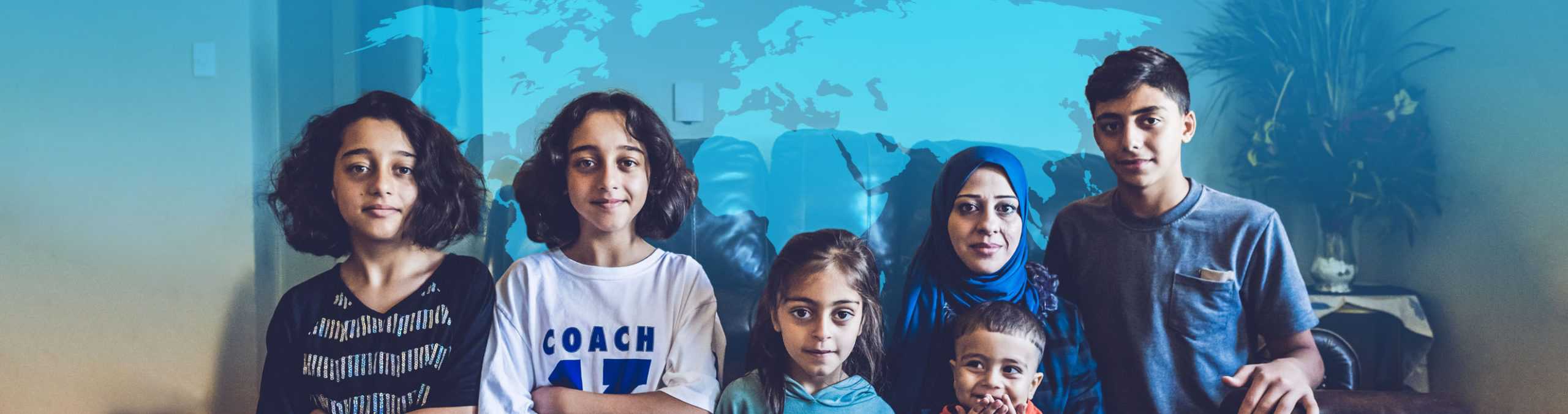 Refugee family sitting on couch with World Relief blue map behind them.