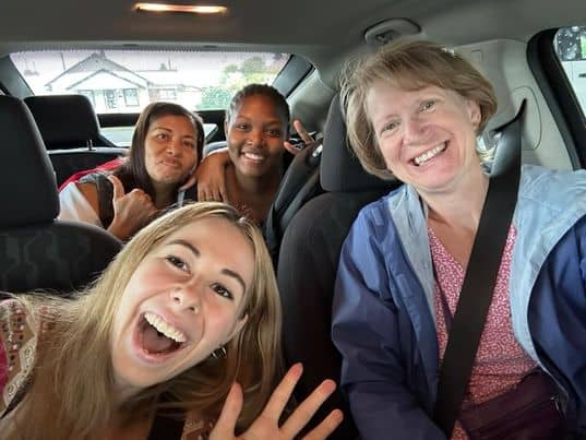 A car volunteer smiles with refugees in the back seat.