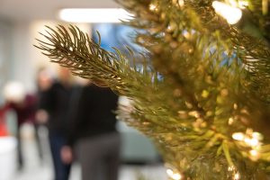 People talk behind a Christmas tree.