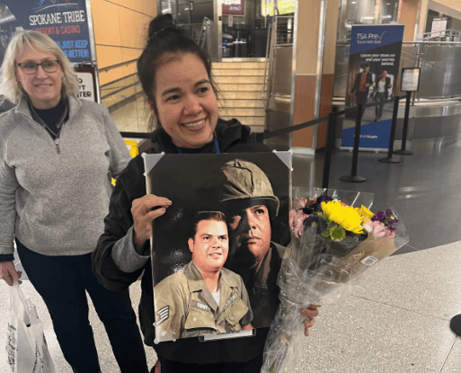 Hoa stands in an airport holding a photograph of her father.