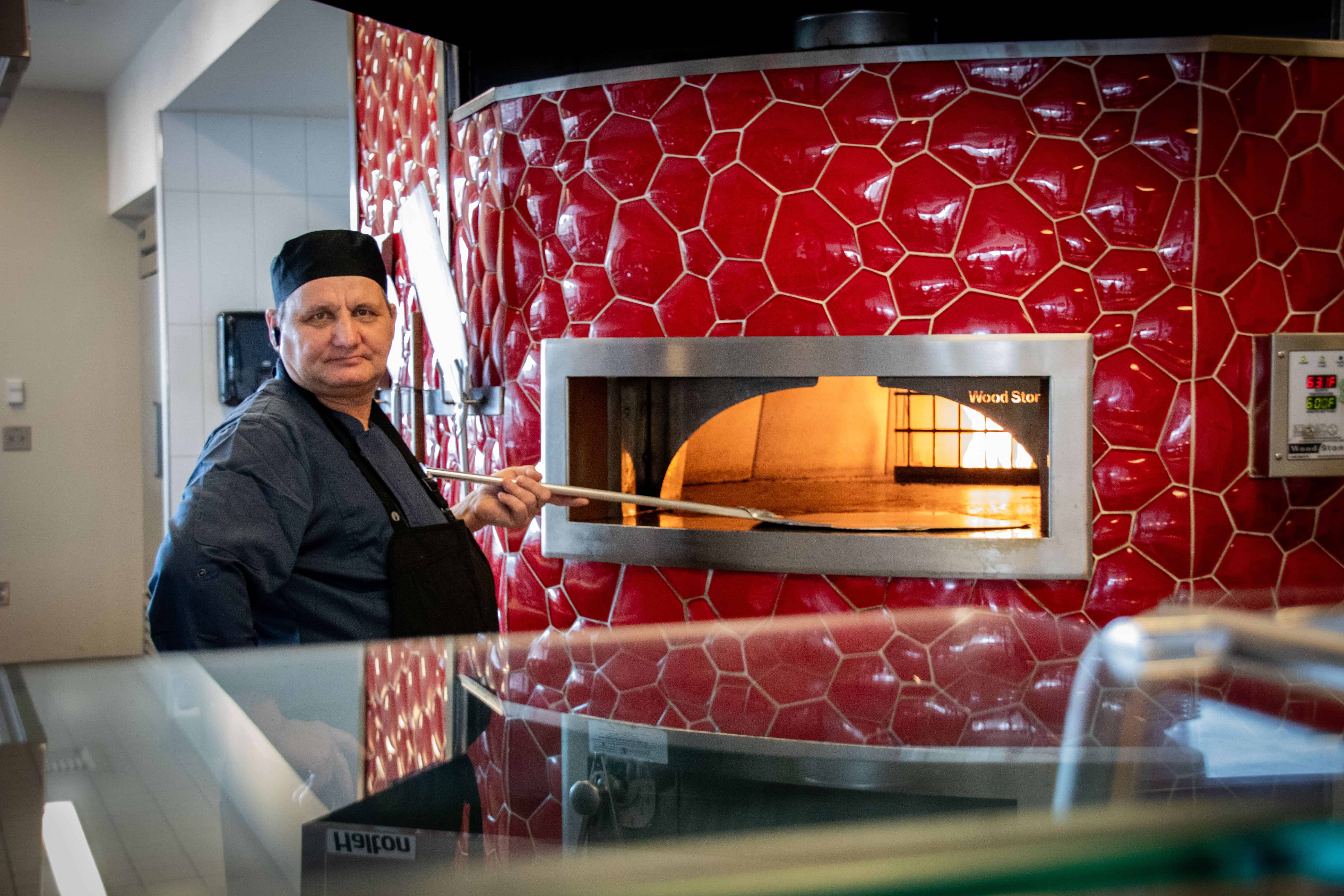 A man standing at a pizza oven.