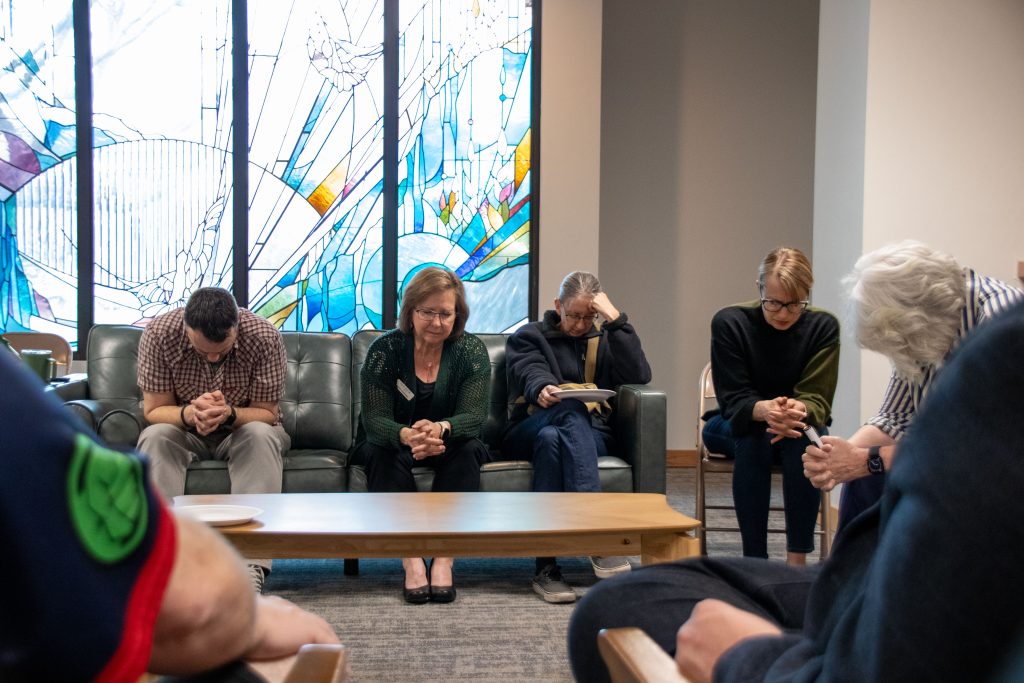 A group of people in prayer for refugees.