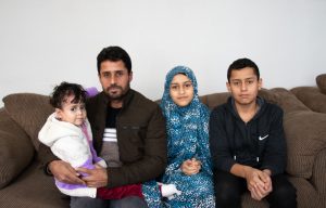Farah sits on the couch alongside her father and siblings.