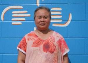 A woman standing in front of a mural wall.