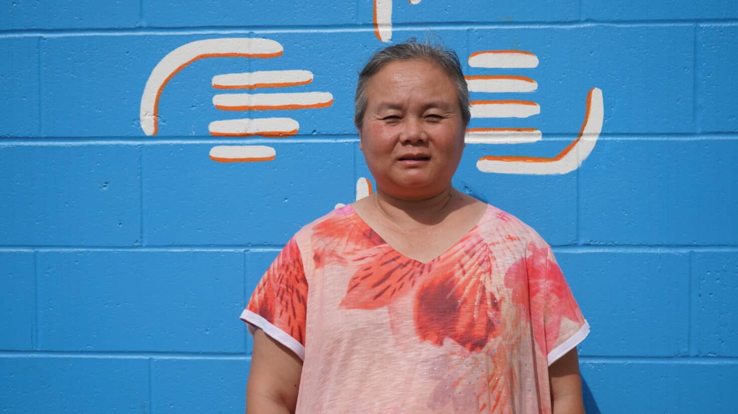 A woman standing in front of a mural wall.