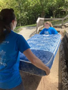 Two female volunteers moving a mattress.