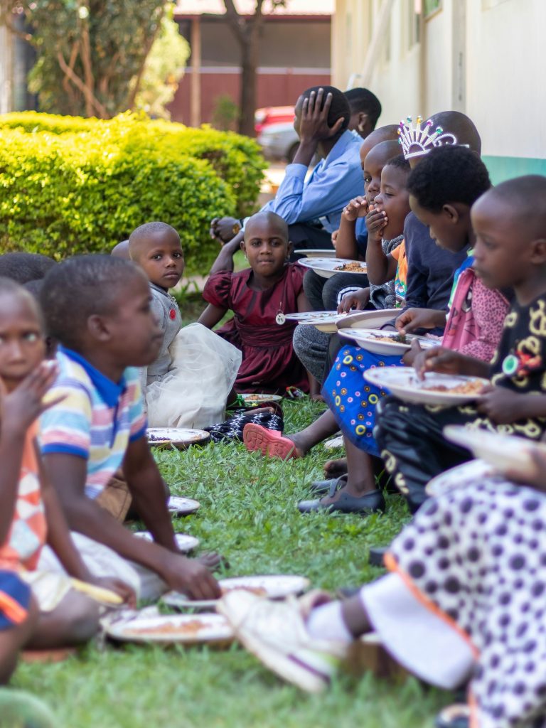 Ugandan children eat food together on the grass