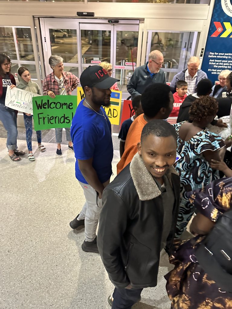 Volunteers hold signs at a midnight airport arrival.