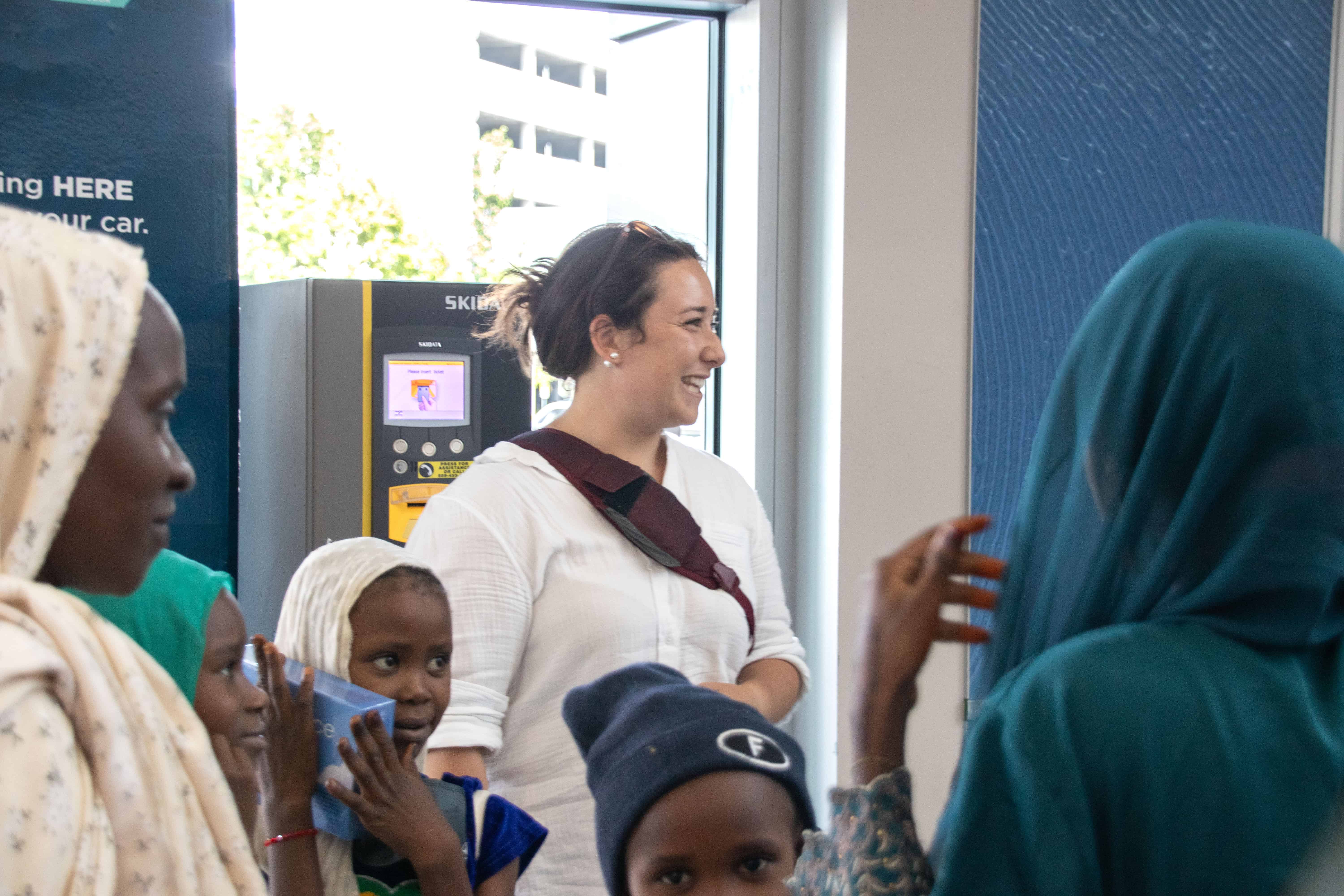 A woman with a smile welcomes refugees at an airport.