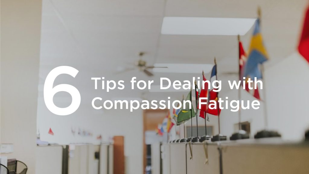 Text - 6 Tips for Dealing With Compassion Fatigue over an image featuring an office and small flags from around the world