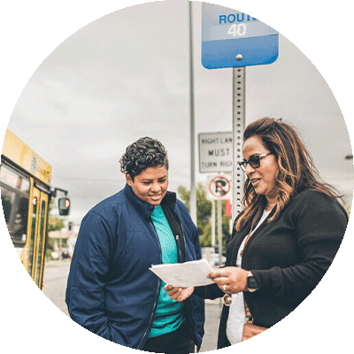 gift-guide-mental-health-transportation two women reading a schedule for a bus route