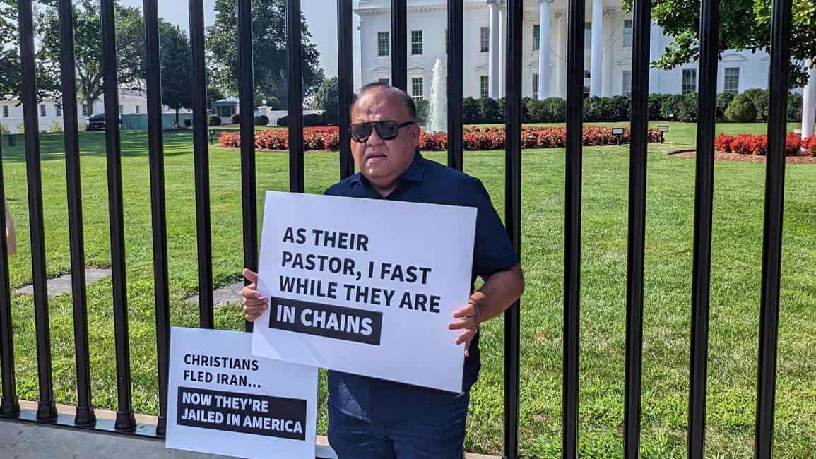 A man in front of the White House holds a sign reading: “As their Pastor, I fast while they are in chains.”