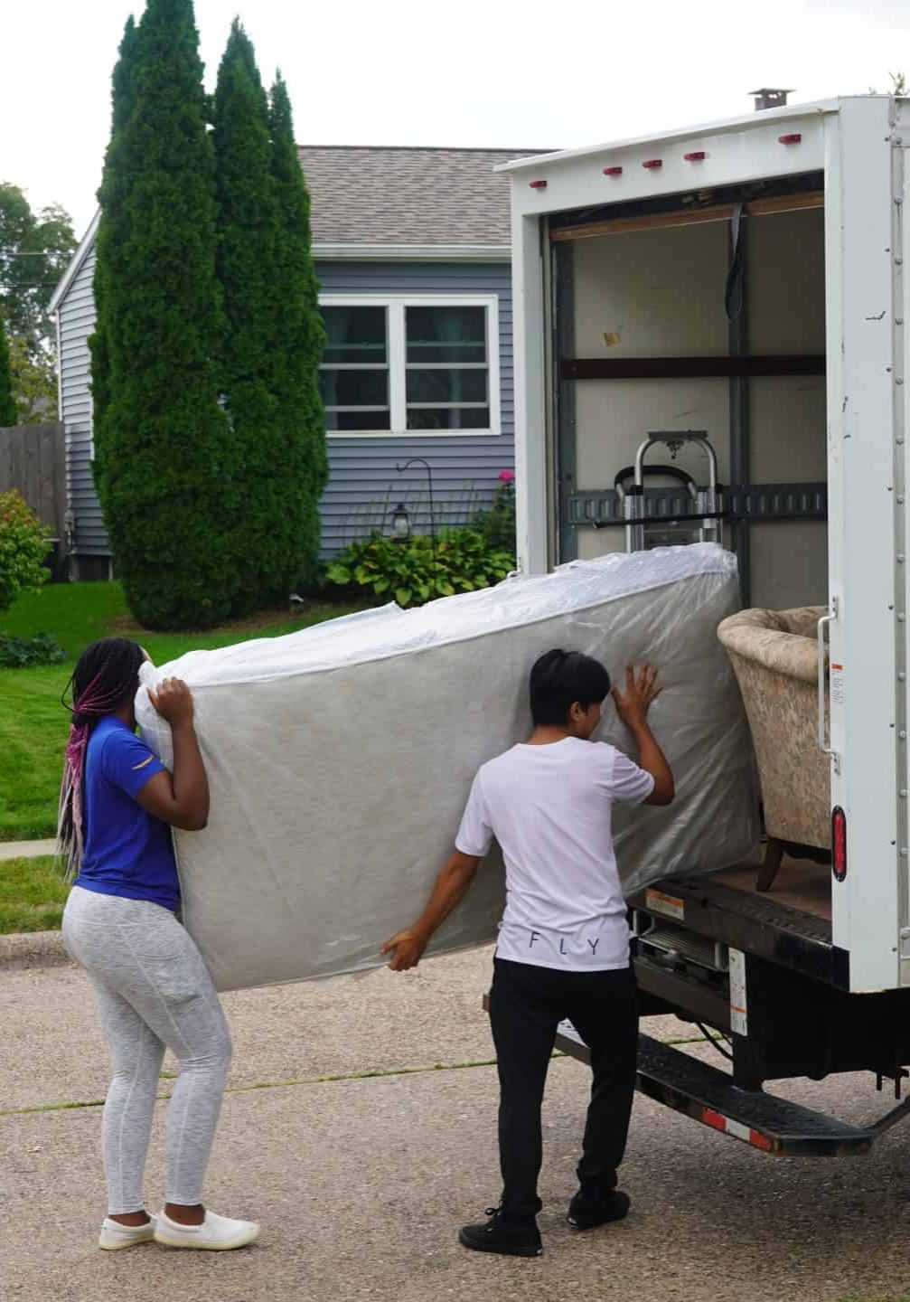 two people carrying a mattress