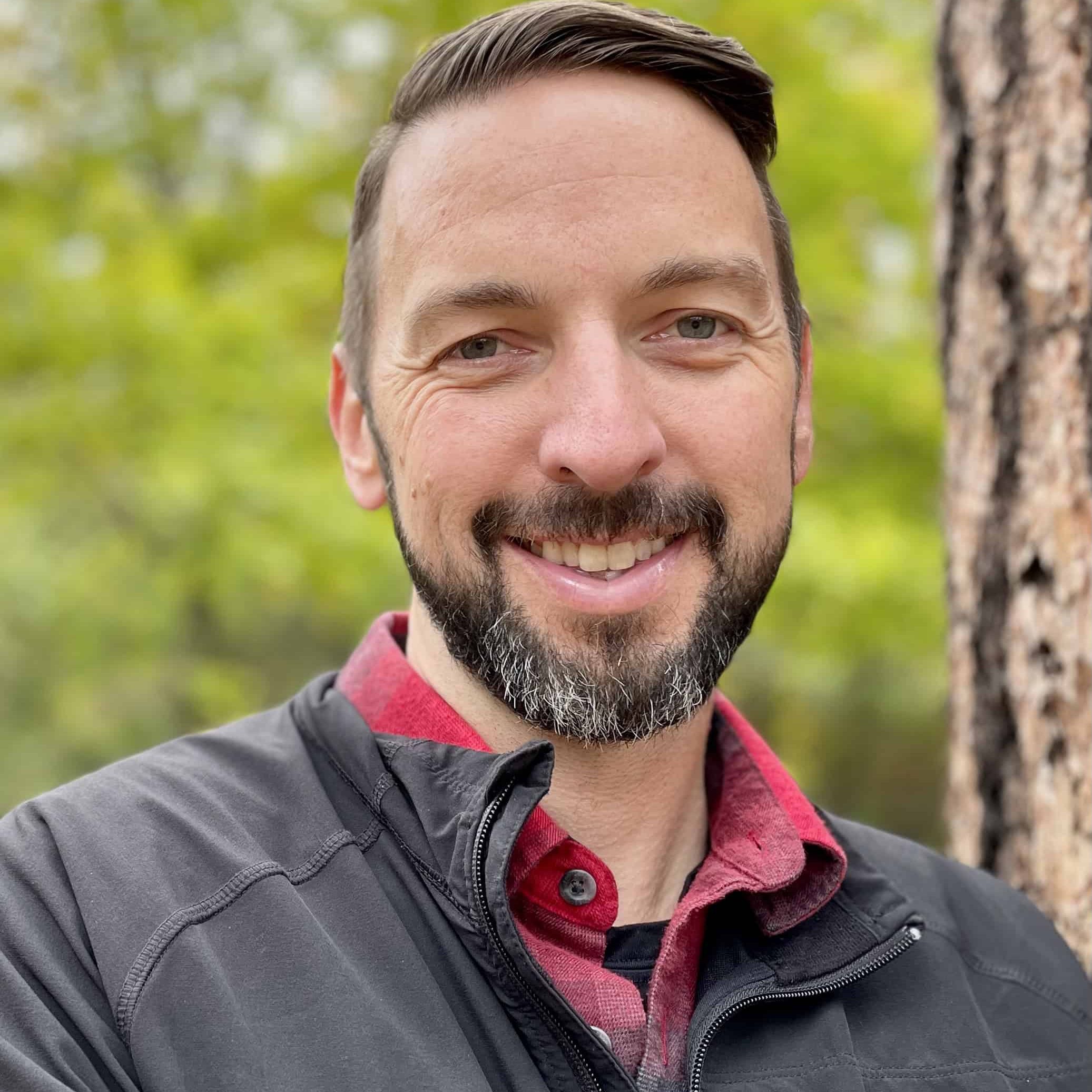 Nathan Thiry, pastor of Faith Bible Church in Spokane, stands next to a tree with green leaves in the background