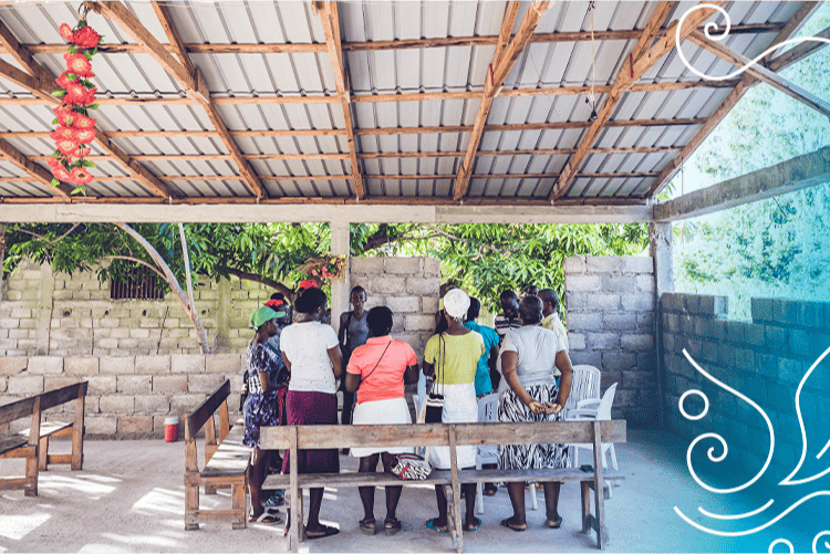 Group of people standing at a table in Africa with Change That Lasts branding