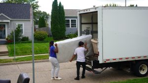 two people carrying a mattress