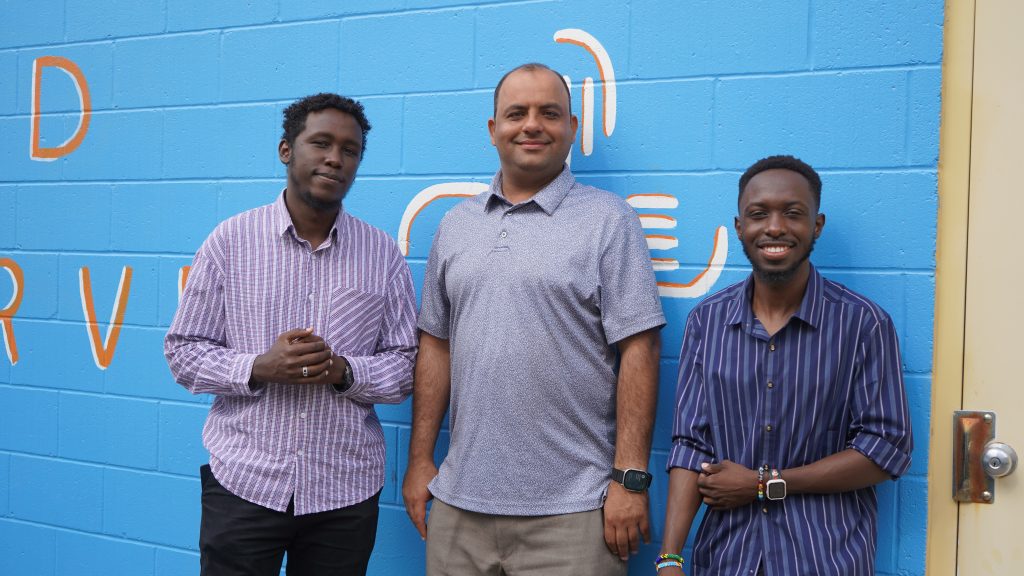 Quad Cities staff members in front of a mural wall.