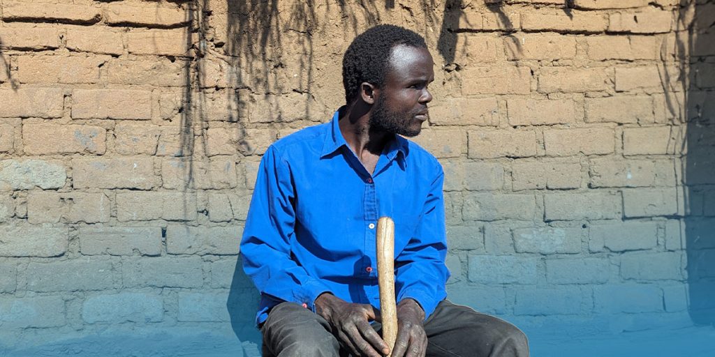 Boniface, a leader and participant in World Relief Malawi's disability inclusion programing, sits holding his staff.