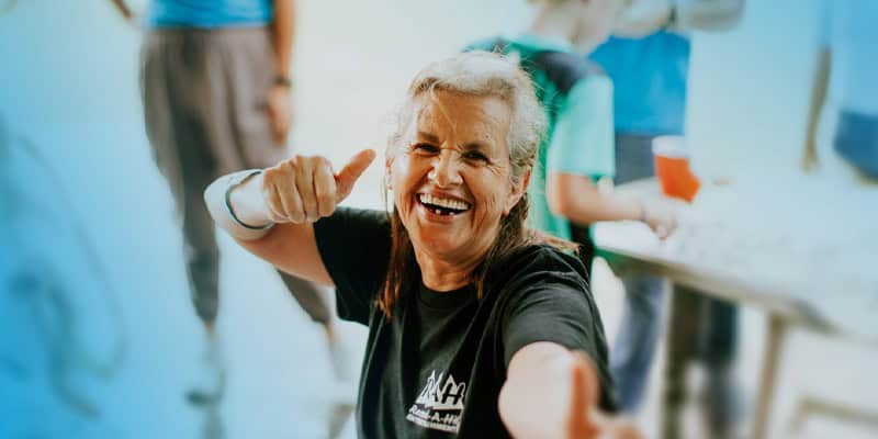 A woman smiles at the camera with a thumbs up