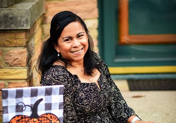 A woman sits on a step and smiles at the camera